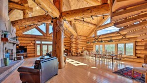 Interno spazioso di una baita di legno, con un'ampia zona pranzo, un camino e un angolo salotto accogliente.