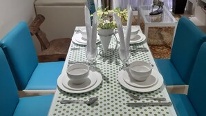A dining area with a table set for four, blue upholstered chairs, and a white tablecloth with green polka dots. - Affordable Luxury 2BR Condo in Davao City (Davao City)