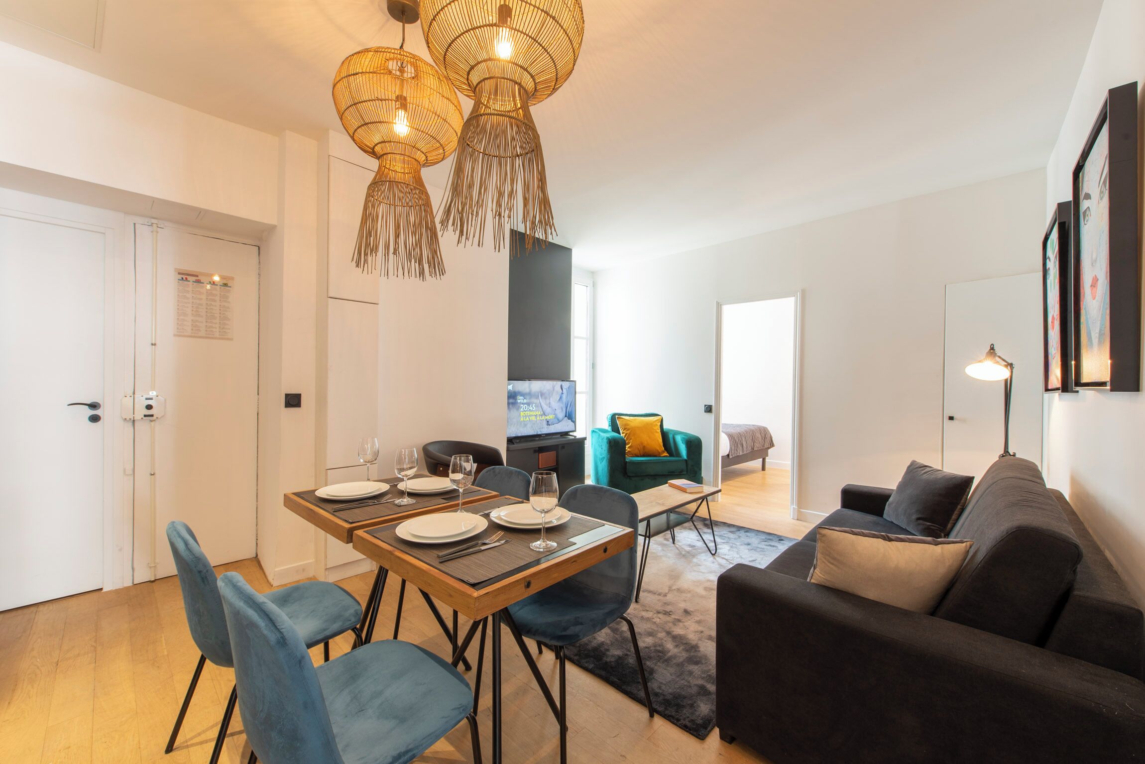 A modern living room with a dining area, featuring a sofa, a coffee table, and a TV.