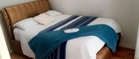 A neatly made bed with a striped bedspread, a blue blanket, and a white pillow.