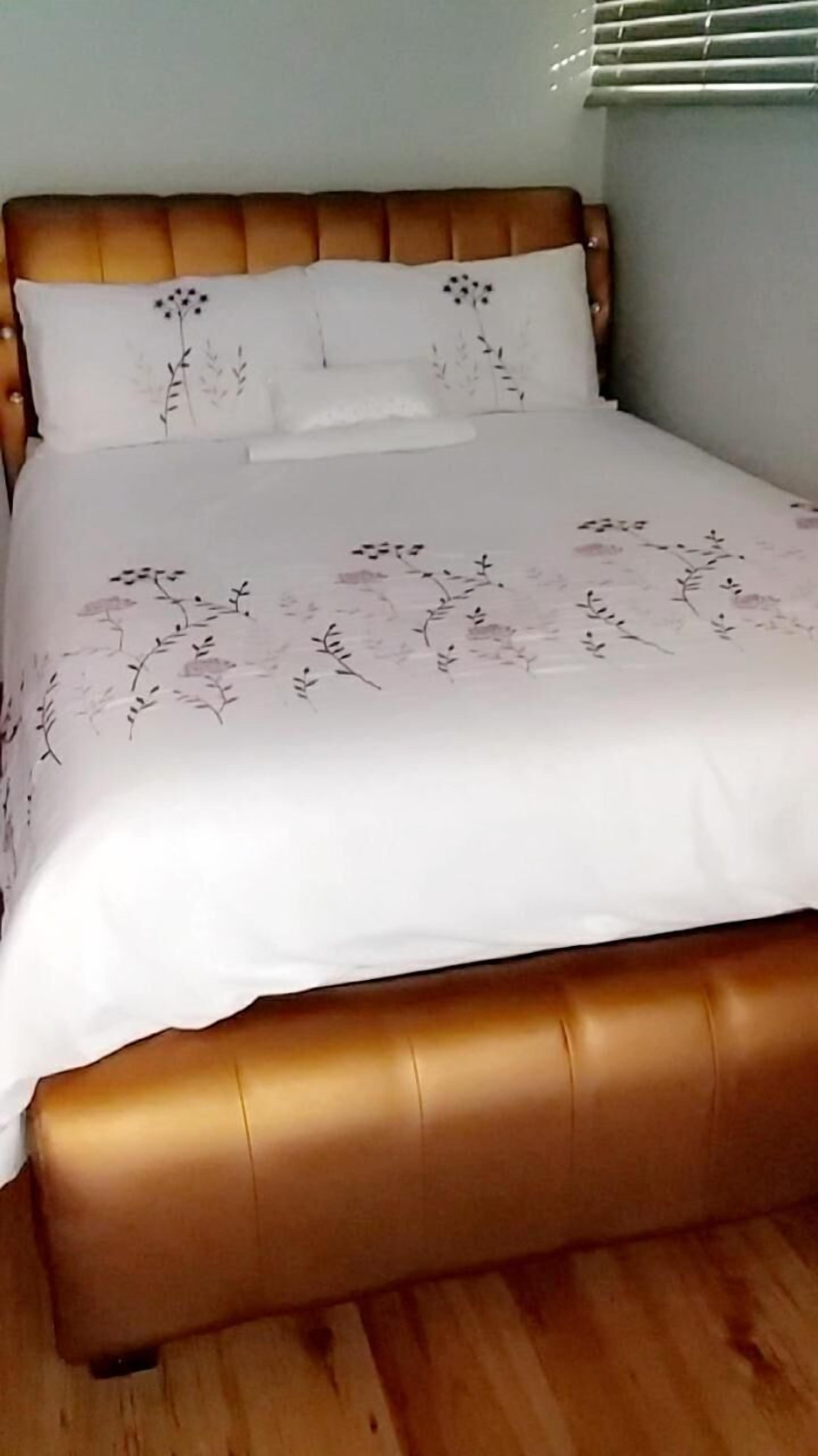 Una cama con cabecera de madera y ropa de cama estampada con motivos florales.
