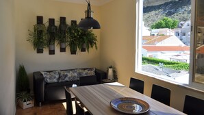 A dining area with a table, chairs, and a view of buildings and a mountain through a large window.
