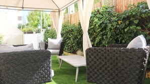 An outdoor patio with wicker furniture, a table, and a canopy.