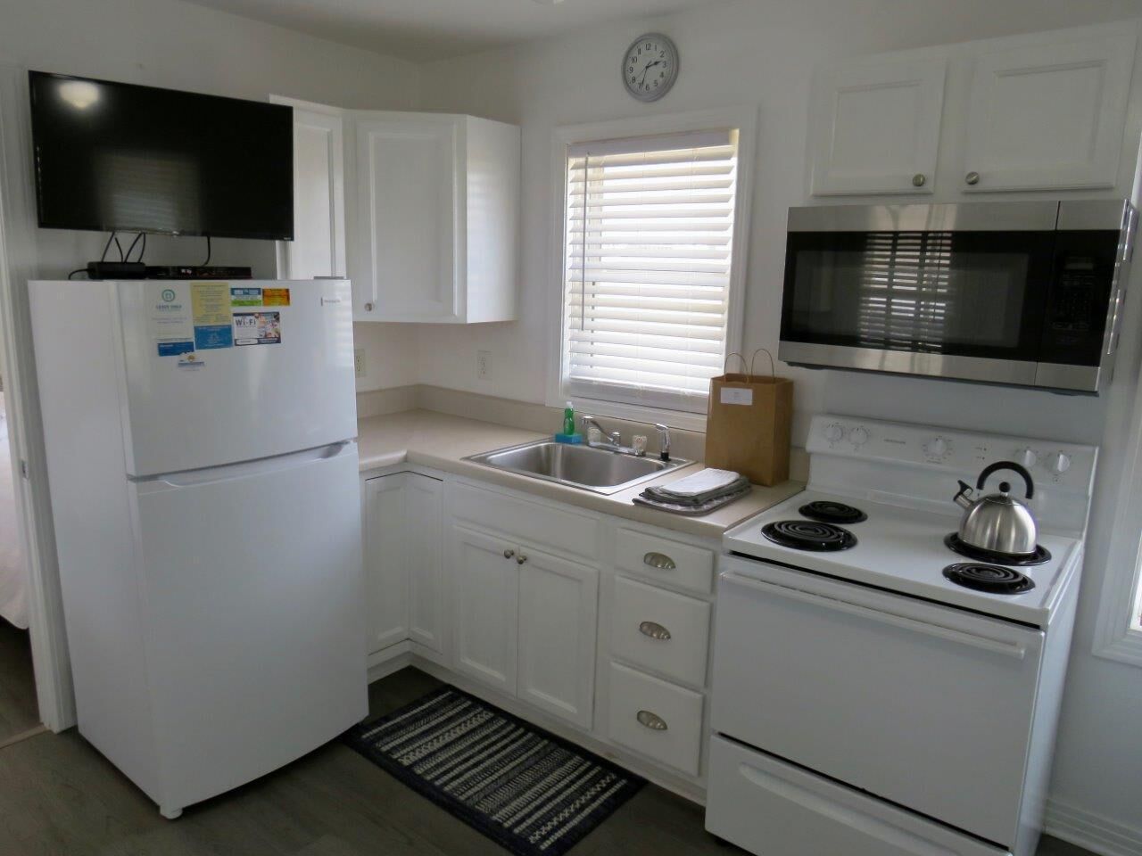A compact kitchen with a refrigerator, microwave, stove, and sink.