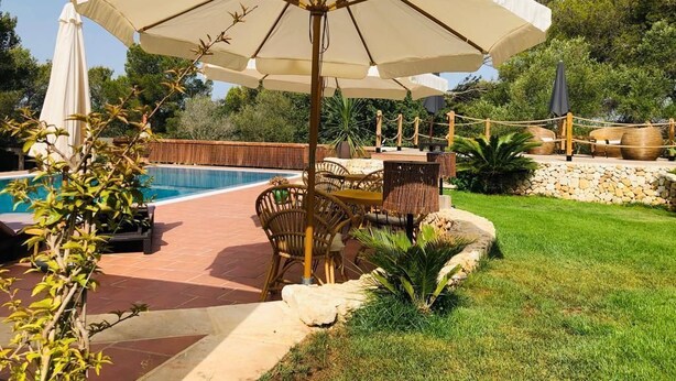 An outdoor pool area with a covered seating area, a wooden fence, and a stone wall. - Guest Room in nature in Minorca : Adults Only (Ferreries)