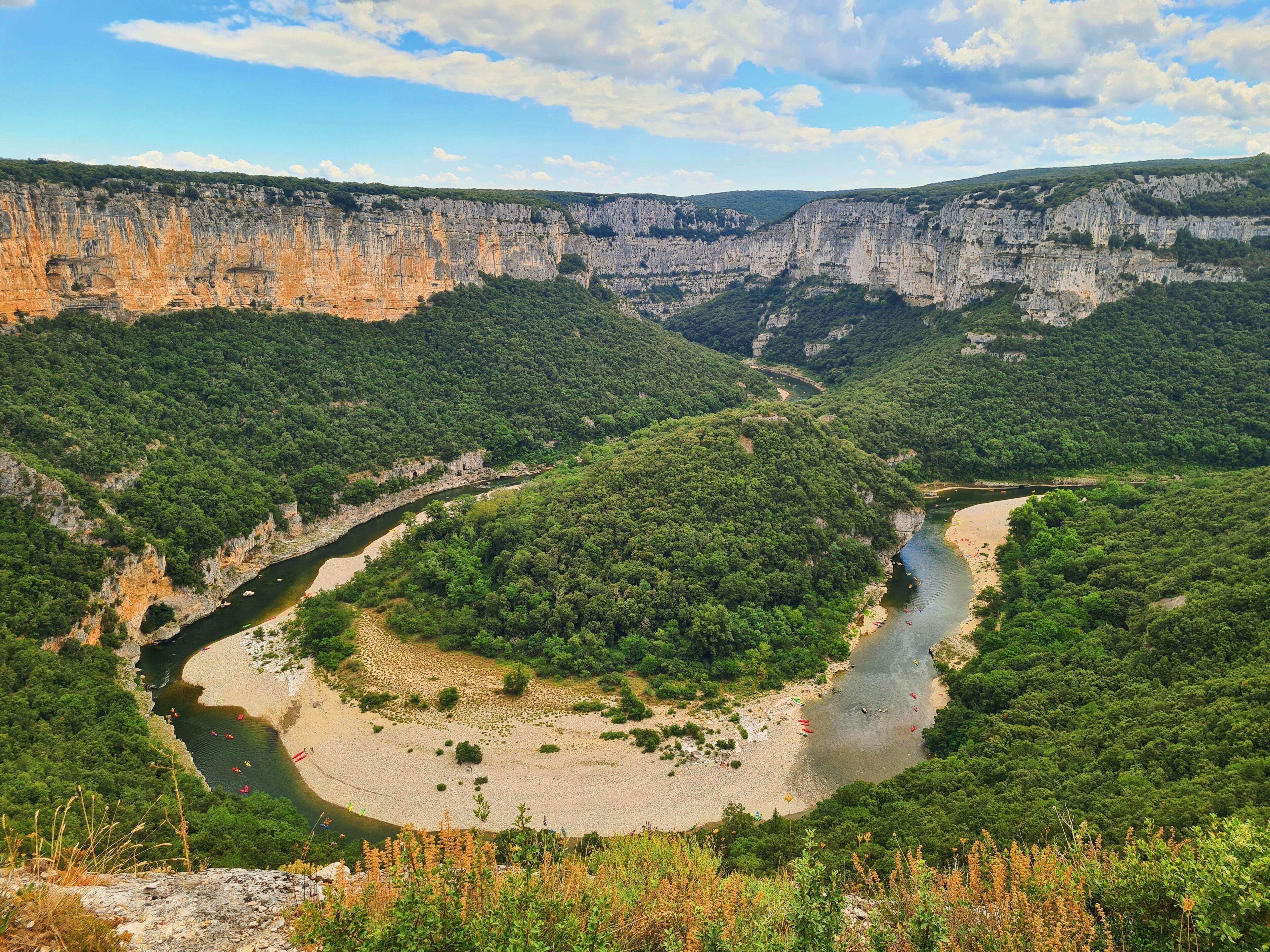 Une rivière serpentant à travers un canyon, avec des falaises et une végétation luxuriante.