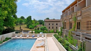 A swimming pool with lounge chairs, a stone building in the background, and lush greenery.