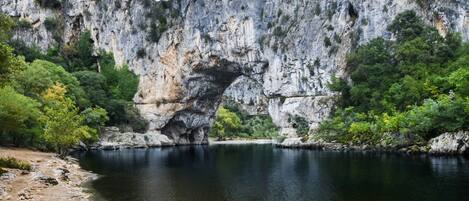 Un paisaje natural con un río, una playa de arena y acantilados rocosos.