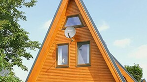 A modern A-frame house with a brick foundation, large windows, and a satellite dish. - House Dina Ahrenshoop (Ahrenshoop)