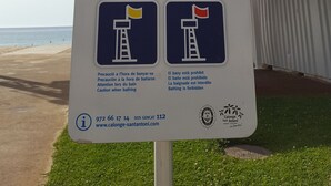 Un panneau indiquant les consignes de sécurité à respecter sur la plage et les coordonnées des services d’urgence.