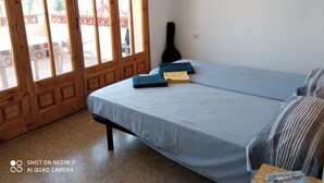 Une pièce avec un lit, une guitare et une table sur laquelle se trouve un stylo.