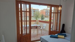 Une chambre avec un lit, une guitare et un balcon équipé d’une table et de chaises.