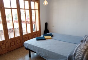 A room with a bed, a guitar, and a table with a pen.