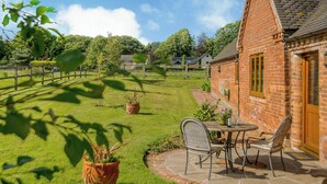 A brick building with a patio, a table, and chairs. - 1 bedroom accommodation in Rufford, near Newark (Rufford, near Newark)