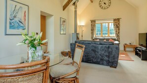 A spacious living area with a large sofa, a dining table with chairs, a chandelier, a clock, and a window with curtains. - 1 bedroom accommodation in Rufford, near Newark (Rufford, near Newark)