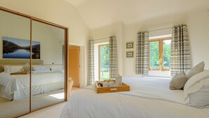 A bedroom with a large mirror, two beds, a wooden door, and a view of greenery outside. - 1 bedroom accommodation in Rufford, near Newark (Rufford, near Newark)