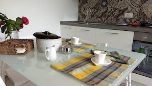 Eine moderne Küche mit Glastisch, weißen Schränken und einer strukturierten Spritzschutzwand.
