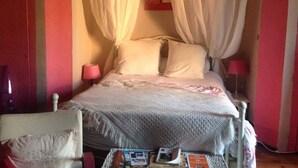 Un dormitorio con cama con dosel, una mesita de noche con lámpara y una silla.