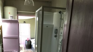 Baño con ducha, lavabo e inodoro. Hay una puerta de madera y una ventana.