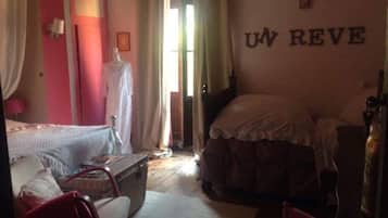 A bedroom with a bed, a chair, a suitcase, and a wall with the letters "UN REVE".