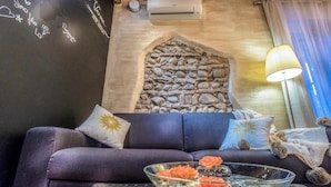 A cozy room with a stone wall, a dark blue sofa, and a glass table with decorative items. - Abbraccio di Romeo e Giulietta (Verona)