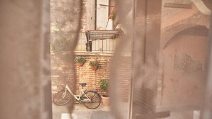 A narrow alley with a bicycle parked against a brick wall, potted plants, and a balcony with a railing. - Abbraccio di Romeo e Giulietta (Verona)