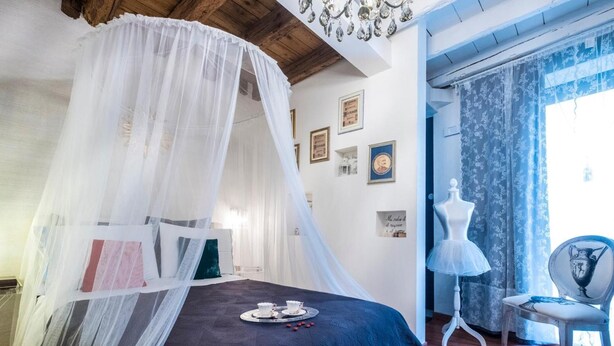 A bedroom with a canopy bed, a mannequin, and a chair. - Abbraccio di Romeo e Giulietta (Verona)