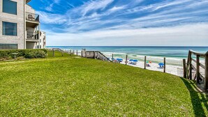 A grassy area leading to a beach with a wooden walkway and a building with balconies. - ☀️Beachfront Complex-Top Floor-30A-Driftwood Cottage (Santa Rosa Beach)