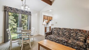 A cozy living room with a patterned sofa, a wooden coffee table, and a dining area with a table and chairs.