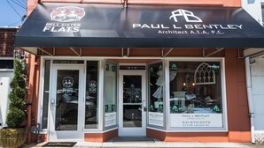 A storefront with a black awning displaying the names 'Bell Sister Flats' and 'Paul L Bentley Architect A.I.A. P.C.' with contact numbers and a door marked '615'.