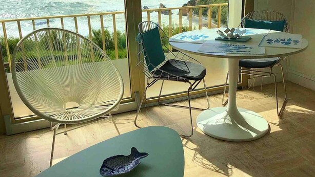 Un balcon avec vue sur l’océan, une table ronde avec des chaises et un aquarium décoratif.