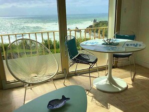 A balcony with a view of the ocean, a round table with chairs, and a decorative fish bowl. - Wide angle on the Ocean, Studio front line facing the Côte des Basques. (Biarritz)