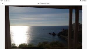 Une vue sur la côte depuis un balcon doté d’une balustrade, avec un ciel dégagé et l’océan à l’horizon.