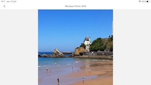 Une scène de plage avec des personnes, un phare et des formations rocheuses.