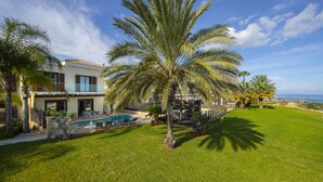 A modern house with a pool, surrounded by palm trees and a well-maintained lawn. - Protaras Seafront Villa El Greco (Protaras)