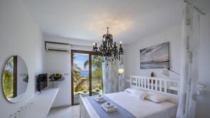 A bedroom with a bed, a chandelier, a painting, and a view of the outdoors. - Protaras Seafront Villa El Greco (Protaras)