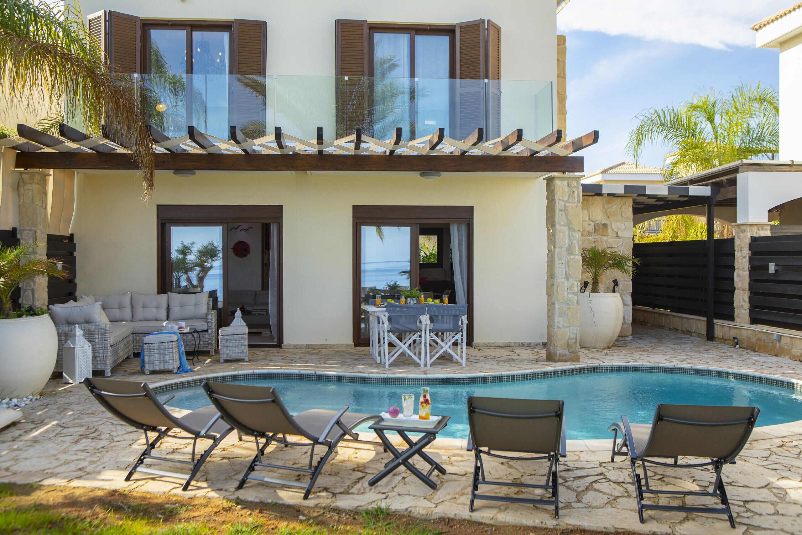 Une maison moderne dotée d’une piscine, d’un espace salon extérieur et d’un patio couvert.