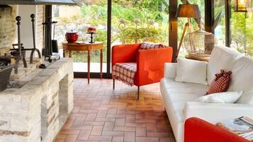 A cozy outdoor seating area with a white sofa, an orange chair, and a red table with a pot.