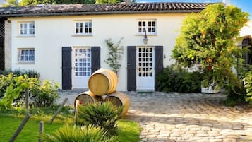 A traditional house with a stone-paved courtyard, a white facade, and a tiled roof.