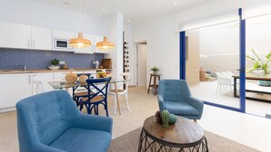 A modern kitchen with white cabinets, a dining area with blue chairs, and a large sliding glass door leading to a patio.