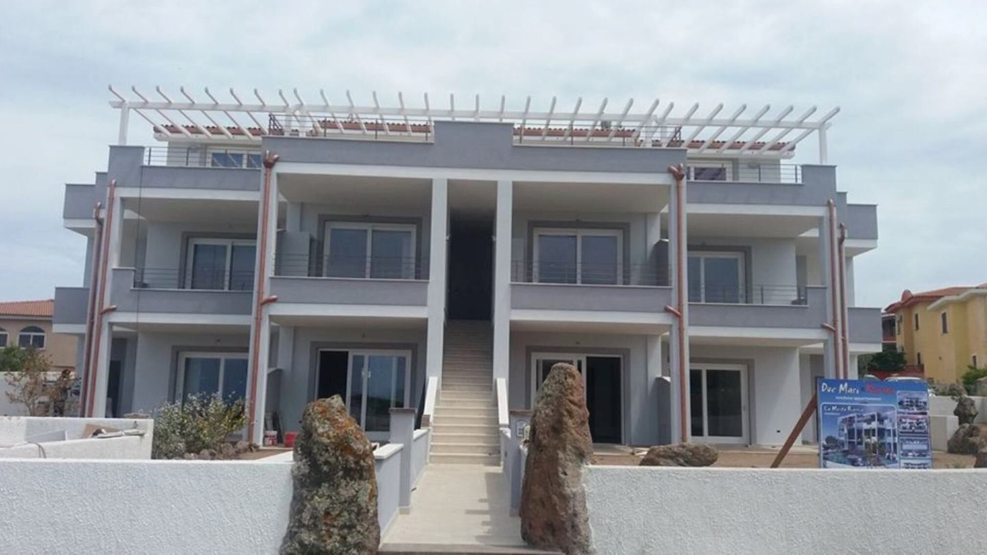 A modern multi-story building with a central staircase leading to the entrance.