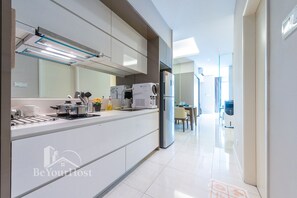 A modern kitchen with a large island, built-in appliances, and a dining area in the background.