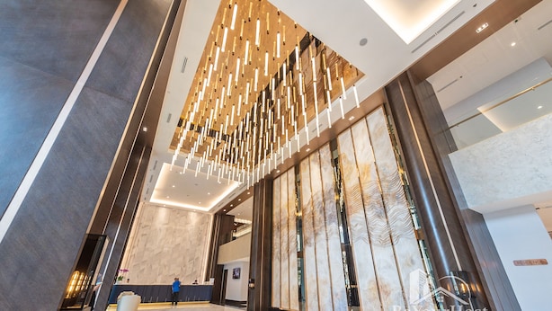 Un moderno vestíbulo de hotel con techo alto, una recepción y un amplio separador de vidrio.