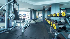 Un gimnasio moderno con diversos equipos de ejercicio, incluyendo una prensa de banca y mancuernas.