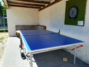 A ping pong table with a dartboard and a green bulletin board on a brick wall. - Guesthouse EJS e.V. Eggesin - single room (room 22) (Eggesin)