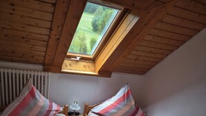 Una stanza accogliente e piccola con due letti di legno, una finestra e un termosifone.
