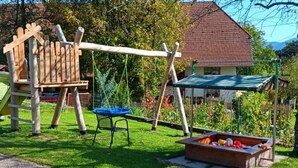 Un'area giochi con altalene, uno scivolo e una sedia blu.