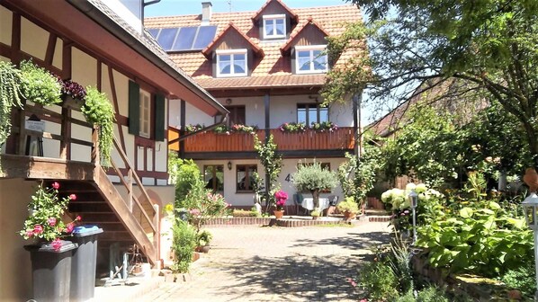 A traditional European-style building with a courtyard, wooden balconies, and potted plants.