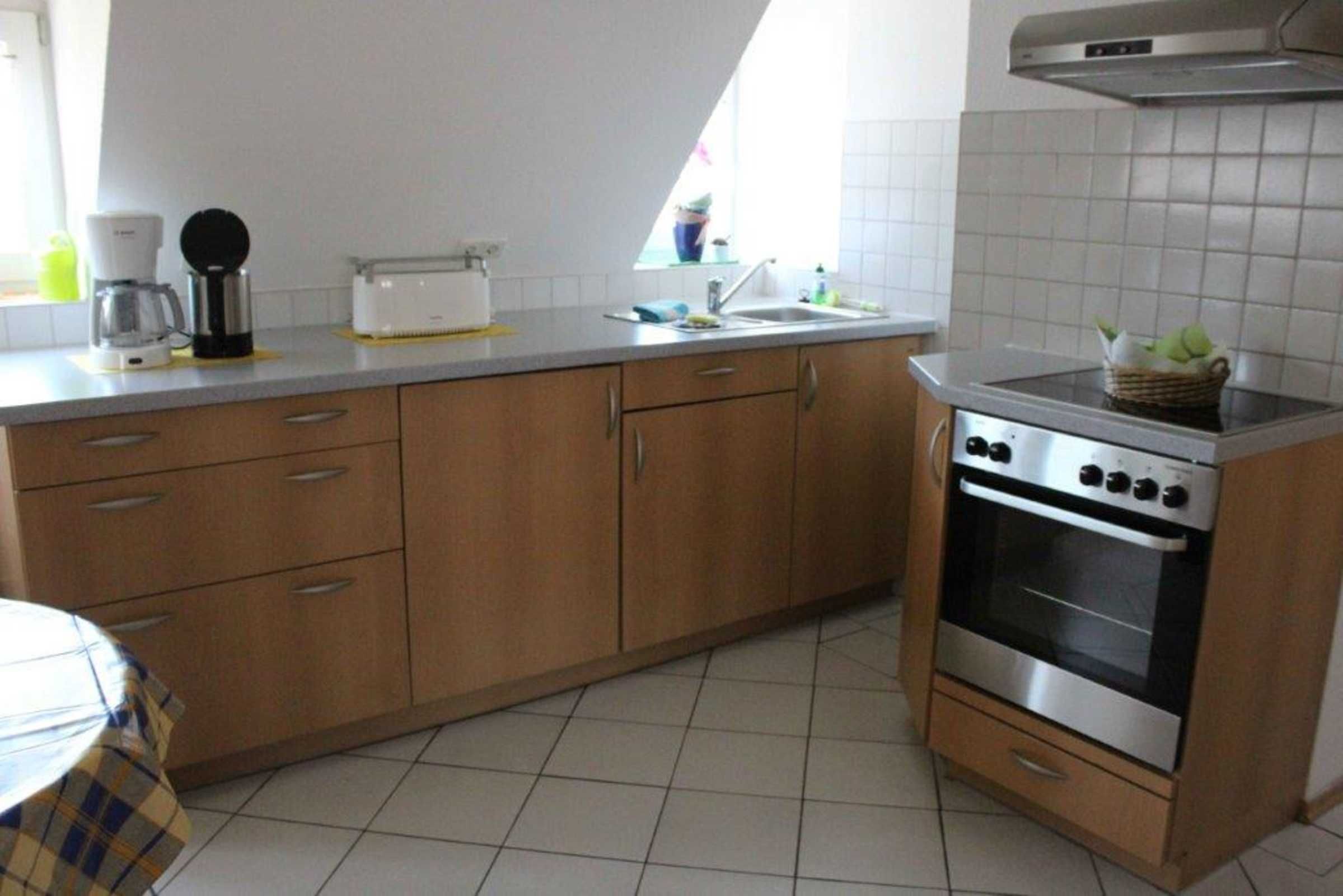 Cozinha com armários de madeira, forno embutido e cafeteira.