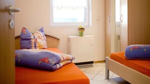 A bedroom with two beds, a window, a radiator, and a wardrobe. - Apartment Hug - Apartment, 4 bedrooms, from 5 persons, max. 7 people (Ringsheim)
